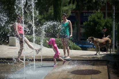 Una familia pasa el calor refrescándose en una fuente de Horta, en Barcelona.