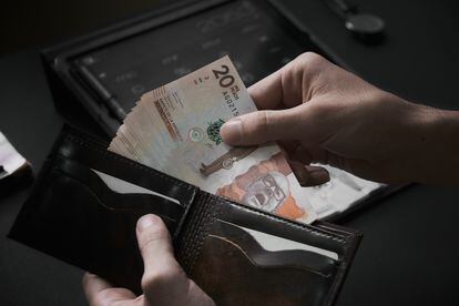En una imagen de archivo, un hombre toma billetes de 20 mil pesos colombianos