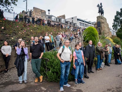 Un grupo de personas observa las salvas en honor a Isabel II, en los jardines de Princes Street, en Edimburgo, este viernes.