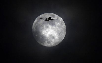 Un avión vuela junto a la luna llena en Londres (Reino Unido).
