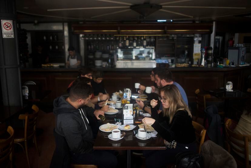 Clientes comen el desayuno en un bar sin electricidad, en Buenos Aires.