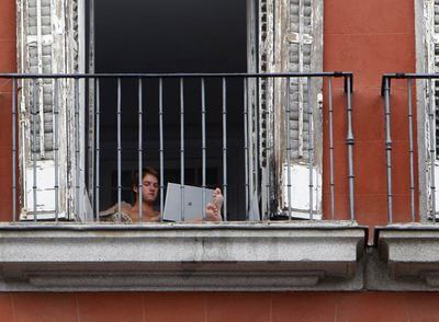 Un joven utiliza un ordenador personal en el balcón de un domicilio que da a la plaza Mayor.
