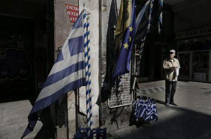 Un ancià davant d'una botiga de banderes gregues i de la UE al centre d'Atenes, aquest dimarts.