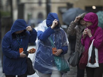 Varias mujeres se protegen de la lluvia y viento con impermeables de plástico, en Sevilla. 
 