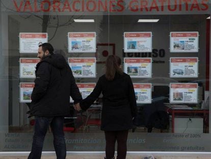 Dos personas miran el escaparate de una inmobiliaria en Madrid.