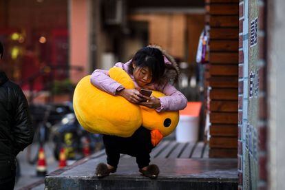 Una mujer usa su m&oacute;vil en las calles de Shangh&aacute;i. 