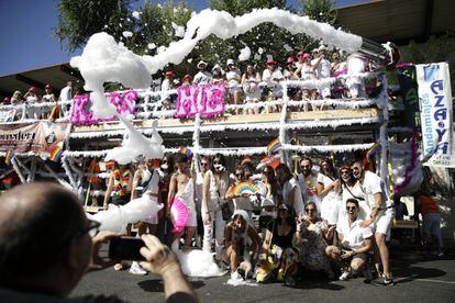 Un grupo de personas posan para una foto junto a una de las carrozas que participarán en el desfile del Orgullo, este sábado en Madrid.
