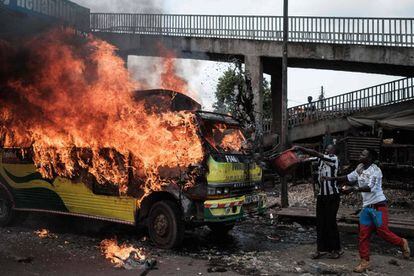 Simpatizantes de la coalición Súper Alianza Nacional (NASA) arrojan agua a un autobús en llamas en Nairobi. Al menos tres personas murieron a causa de disparos durante una manifestación a favor del líder opositor Raila Odinga que la policía trató de dispersar.