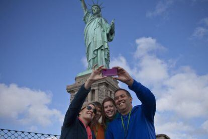 Turistas se fotografían con la estatua de la Libertad tras su reapertura.