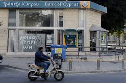 Un hombre circula ayer en motocicleta delante de una sucursal del Banco de Chipre en Nicosia (Chipre).