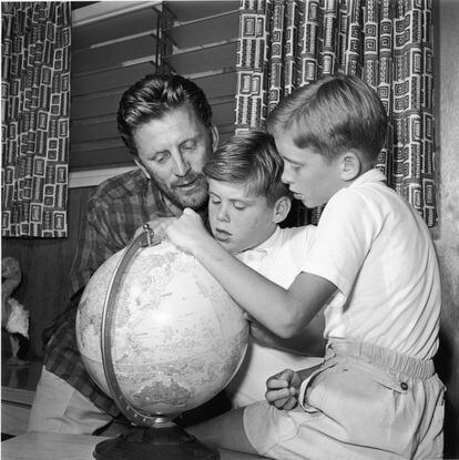 Kirk Douglas mira una bola del mundo en su casa de California, junto a dos de sus hijos, Joel (centro) y Michael en 1956.