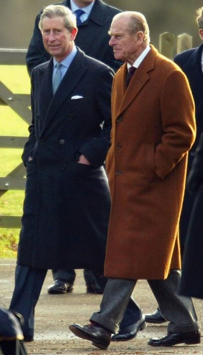 El príncipe Carlos de Inglaterra (izquierda) junto a su padre, el Duque de Edimburgo, el día de Navidad en la iglesia Sandringham en Norfolk (2003). Como se aprecia en la fotografía, los abrigos de paño largos son una prenda característica del estilo de padre e hijo.