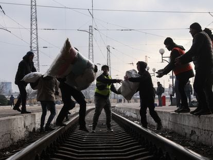 Voluntarios transportan sobre las vías del tren ayuda médica y artículos de primera necesidad en la estación de tren de Lviv, en el oeste de Ucrania.