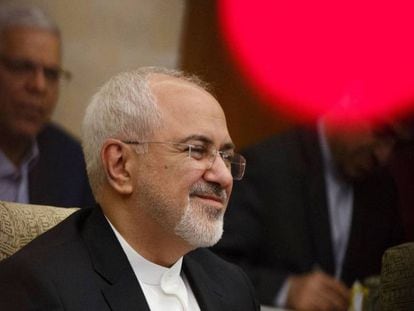 El ministro de Exteriores iraní, Mohammad Javad Zarif, este domingo en Pekín. En vídeo, un grupo de diputados iraníes quema una bandera estadounidense la semana pasada en el Parlamento.