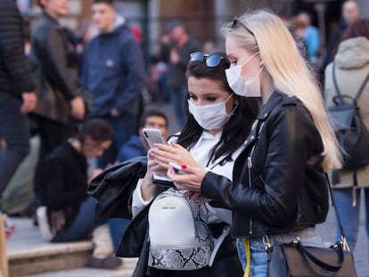 Dues dones consulten el mòbil protegides del coronavirus amb màscares, a la Piazza della Rotonda, a Roma.