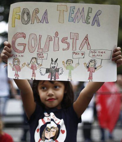 Una niña muestra un cartel que recoge la gran broma brasileña del último año: que el actual presidente es en realidad un vampiro