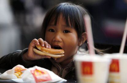Una niña come una hamburguesa en un establecimiento de McDonald's en Milán, Italia.