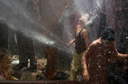 Niños se refrescan con agua proveniente de cañerías después de perforarlas en protesta contra los apagones en su área, en Karachi, Pakistán.
