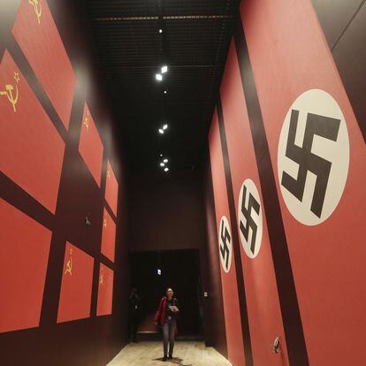 Una mujer camina por un pasillo con banderas de la Alemania nazi y de la URSS.