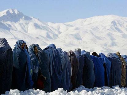 Viudas afganas cubiertas con el <i>burka</i> se alinean para conseguir raciones de comida ante un centro de distribución de una organización internacional en Kabul.