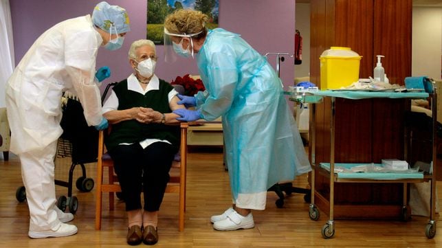 Carer Monica Tapias (L), 48, talks with Araceli Hidalgo (C), 96, a resident of Los Olmos nursing home for the elderly, after receiving a dose of the Pfizer-BioNTech Covid-19 vaccine on December 27, 2020, in Guadalajara, becoming the first two persons vaccinated against coronavirus in Spain. - Araceli Rosario Hidalgo Sanchez, a 96-year-old living in a care home in central Spain became the first person in the country to be vaccinated against Covid-19 today, in an event broadcasted by national television. Carer Monica Tapias followed as the second Spaniard to receive the Pfizer-BioNTech vaccine. (Photo by Pepe Zamora / POOL / AFP)