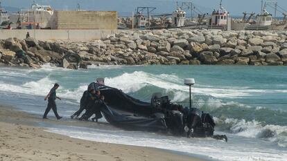 Agentes de la Guardia Civil arrastran una lancha abandonada por los narcos tras una persecución, en la playa del Tonelero, en La Atunara (Cádiz).
