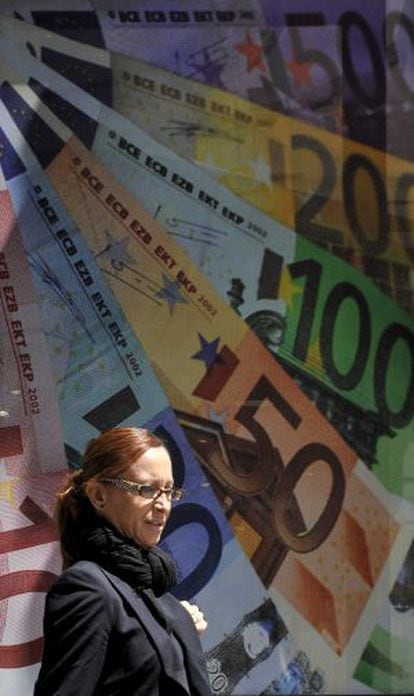 Una mujer pasa frente a un cartel con la imagen de billetes de euro, en Londres.