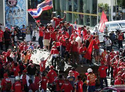 Un grupo de manifestantes antigubernamentales celebra la toma de un vehículo militar en Bangkok. El primer ministro tailandés, Abhisit Vejjajiva, ha anunciad hoy el estado de excepción en la capital tailandesa y otras cinco provincias vecinas.