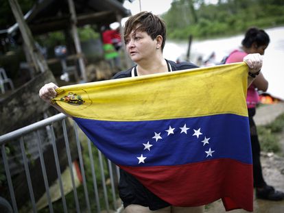 Karina Silva, una médica cirujana venezolana de 41 años, muestra la bandera de Venezuela a su llegada el 13 de octubre de 2022, al pueblo de Bajo Chiquito (Panamá), tras cruzar la selva del Darién