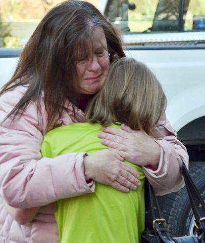 Una madre abraza a su hija a las puertas del colegio Sandy Hook.