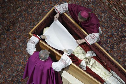 Los obispos Georg Gaenswein, a la derecha, y Diego Ravelli cubren el rostro del papa emérito Benedicto XVI con un velo de seda blanca en el interior de la basílica.