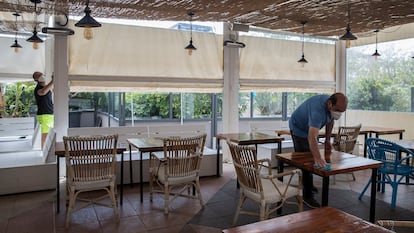 Un empleado de un restaurante limpia las mesas antes de la llegada de los clientes.