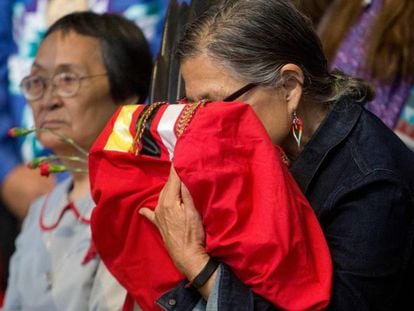 Una anciana indígena canadiense sostiene una copia del informe final sobre el genocidio que ha sufrido su pueblo, el tres de junio en Quebec. En vídeo, el primer ministro canadiense, Justin Trudeau, reconoce el genocidio, el pasado tres de junio.