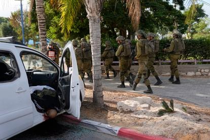 Soldados israelíes pasaban junto al cadáver de un civil tiroteado en su vehículo en la ciudad de Sderot.