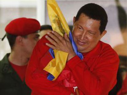 Ch&aacute;vez abraza la bandera venezolana.