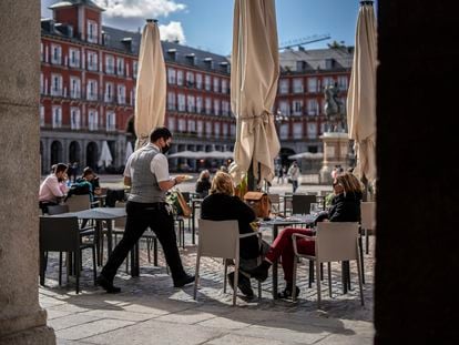 Un camarero atiende a unas clientas en la plaza Mayor de Madrid, este lunes.