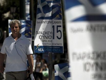 Un hombre camina junto a varios carteles del partido conservador griego Nueva Democracia (ND), hoy en Atenas.