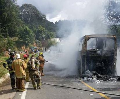 Bomberos apagan el fuego de un autobús de pasajeros en Michoacán.