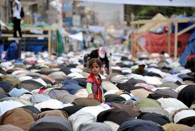 Una niña se alza entre decenas de opositores que rezan en Saná tras una manifestación contra el presidente Saleh. / yahya arhab (efe).