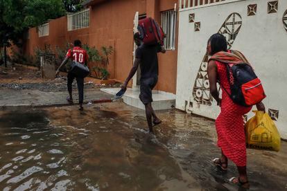 Tres vecinos de Grand Dakar cargan con sus maletas por una calle inundada. Los ciudadanos reclaman que el presidente senegalés, Macky Sall, cumpla con la promesa que hizo al llegar al poder en 2012 de arreglar el problema de fondo: mejorar los sistemas de evacuación de aguas pluviales para que las inundaciones dejen de ser una amenaza anual.