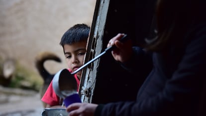 Una mujer sirve arroz con leche a un niño de escasos recursos, en Quilmes (Argentina), el 28 de mayo de 2020.