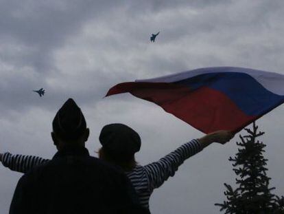 Una mujer ondea una bandera rusa en Sebastopol ante la presencia de aviones rusos en la celebración del Día de la Victoria.
