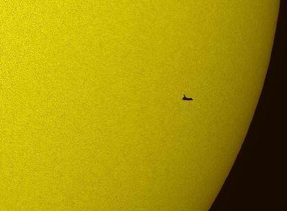 La silueta del transbordador 'Atlantis' recortada contra el Sol en una imagen tomada desde la Tierra
