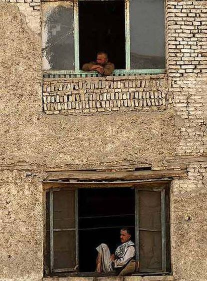 Dos afganos observan por la ventana en un edificio de Kabul.