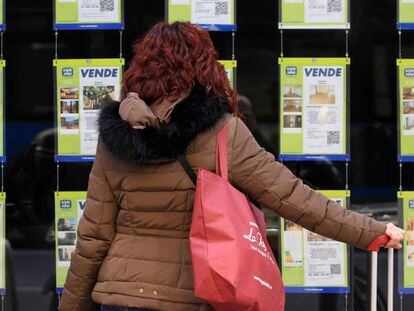 Una mujer examina los carteles de una agencia inmobiliaria en Madrid.