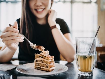 Una mujer disfruta de una tarta con té helado en una cafetería.