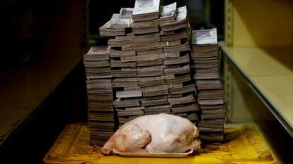 Un pollo de 2,4 kilos frente a una montaña de billetes que suman su precio —un equivalente de 1,95 euros—, en un mercado de Caracas, el 16 de agosto de 2018.