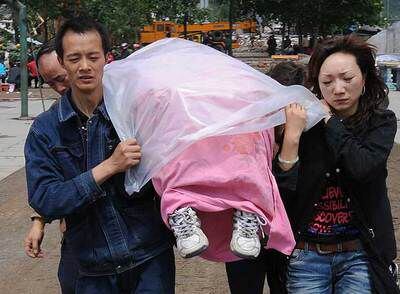 Una pareja lleva el cadáver de su hijo, que acaba de ser rescatado de entre los escombros de una escuela en la ciudad de Hanwang. / afpTraslado del cadáver de una niña muerta en un colegio de Hanwang.