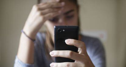 Una adolescente revisa un mensaje de móvil.