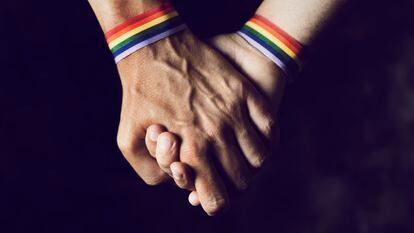 Dos hombres se dan la mano con una pulsera del orgullo LGTBI en sus muñecas.